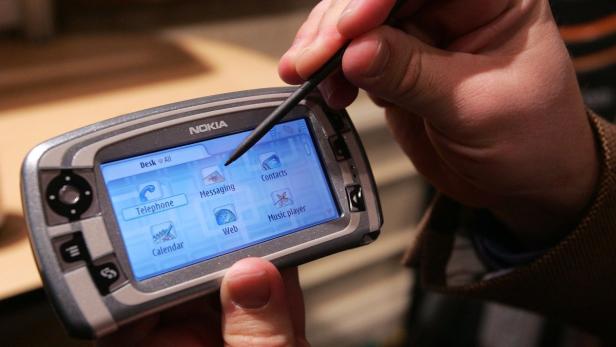 Eine Hand bedient ein älteres Nokia-Smartphone mit einem Stift.
