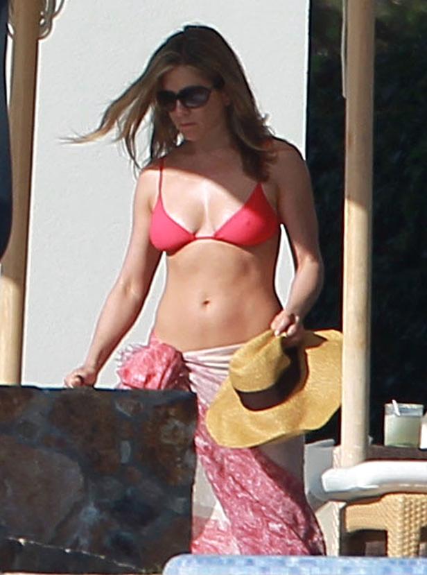 Jennifer Aniston am Strand mit rotem Bikini und Sonnenhut.