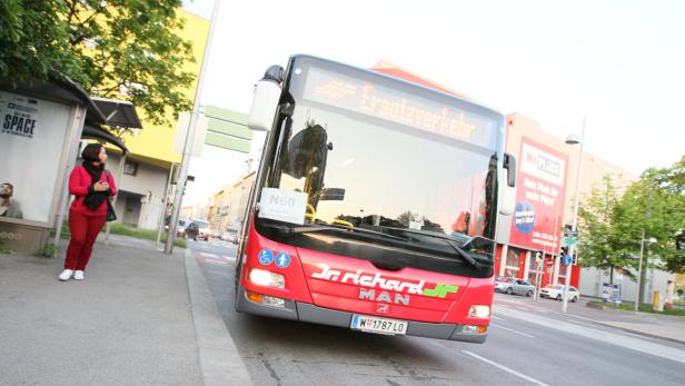 Ein roter Bus der Firma Dr. Richard steht an einer Haltestelle in Wien.