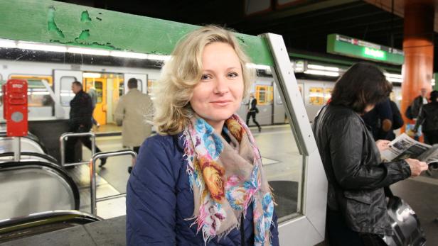 Eine Frau mit blonden Haaren und einem bunten Schal in einer U-Bahn-Station.