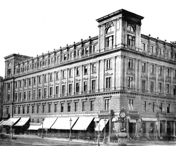 Ein großes, mehrstöckiges Gebäude mit vielen Fenstern und einem Café im Erdgeschoss.