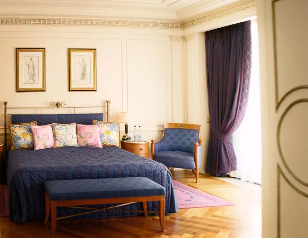 Ein Schlafzimmer mit einem blauen Bett, einem Sessel und einem Fenster mit Vorhängen.