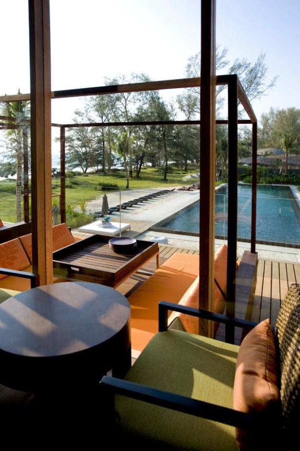 Blick von einer Terrasse auf einen Pool und den Strand.