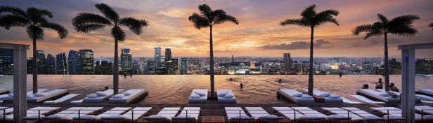 Blick vom Infinity-Pool des Marina Bay Sands Hotels auf die Skyline von Singapur bei Sonnenuntergang.
