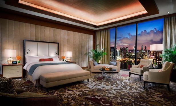 Ein luxuriöses Hotelzimmer mit Blick auf die Skyline einer Stadt bei Nacht.