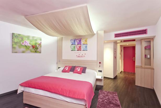 Ein Hotelzimmer mit einem Doppelbett und rosa Akzenten.