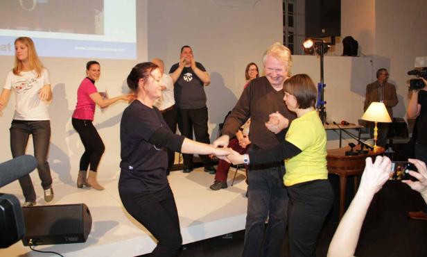 Menschen tanzen auf einer Bühne bei einer Veranstaltung.