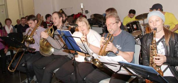 Eine Gruppe von Musikern spielt verschiedene Blasinstrumente und Schlagzeug.