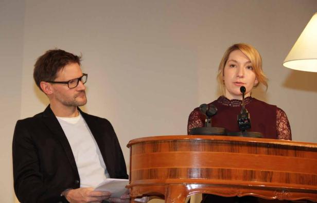 Eine Frau spricht an einem Rednerpult, während ein Mann ihr zuhört.