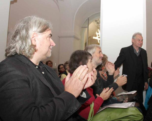 Einige Personen applaudieren in einem hellen Raum.