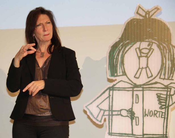 Eine Frau gestikuliert neben einer Pappfigur mit der Aufschrift „Worte“.