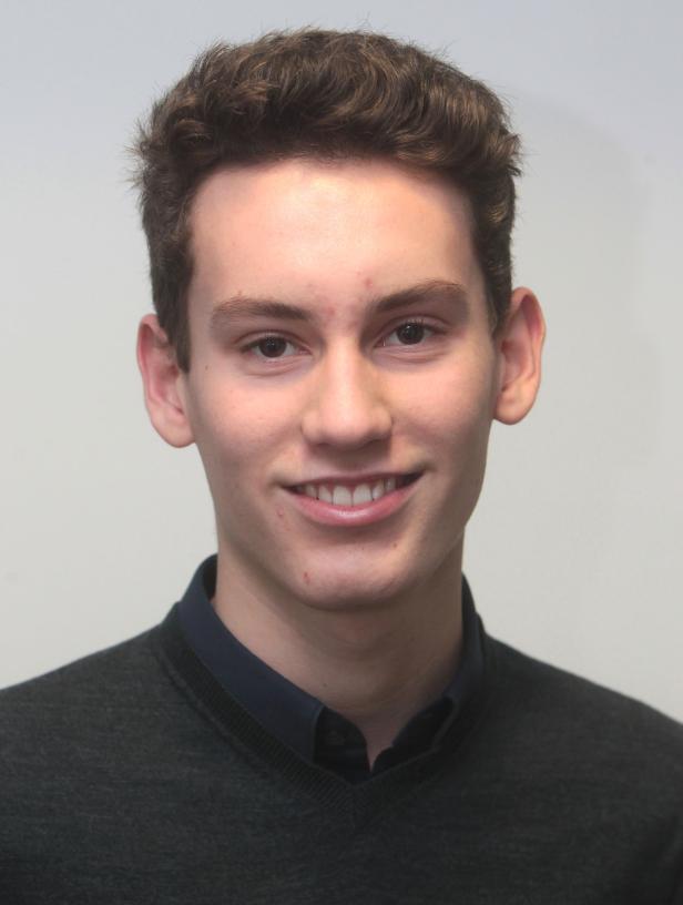 Porträt eines lächelnden jungen Mannes mit braunen Haaren.