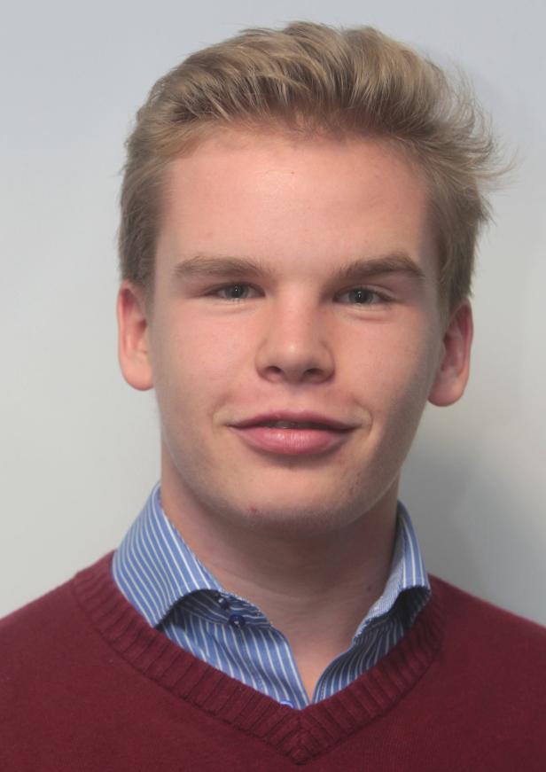 Ein junger Mann mit blonden Haaren und einem roten Pullover lächelt.