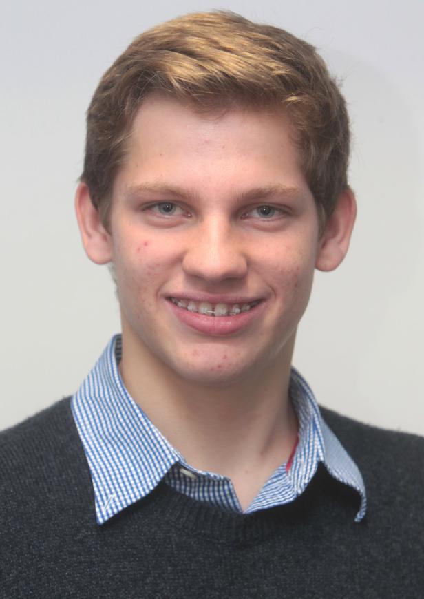 Ein junger Mann mit Zahnspange lächelt in die Kamera.