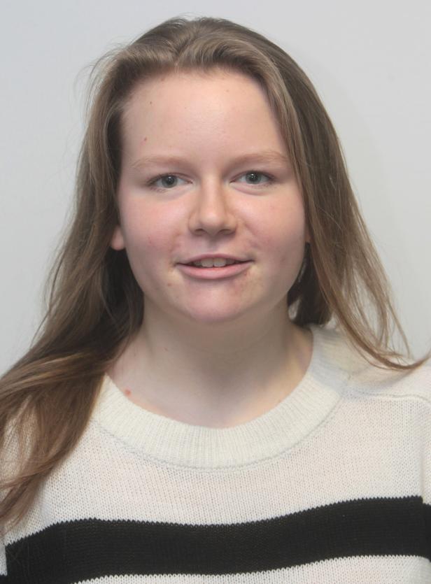 Eine junge Frau mit langen, hellbraunen Haaren und einem gestreiften Pullover lächelt.