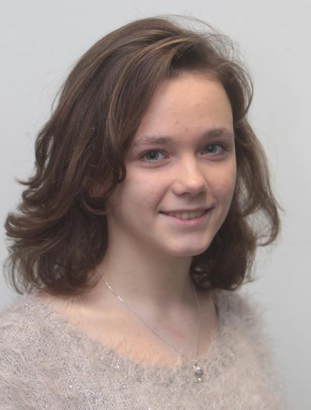 Porträt einer lächelnden jungen Frau mit braunem, gewelltem Haar.