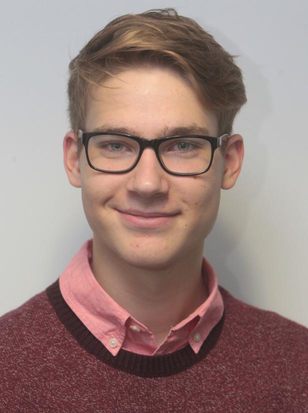 Ein junger Mann mit Brille und blonden Haaren lächelt.