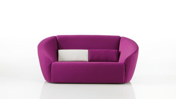Ein lilafarbenes Sofa mit zwei Kissen steht vor einem weißen Hintergrund.