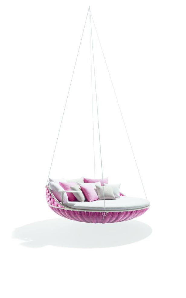 Ein hängendes, rundes Bett mit rosa Geflecht und mehreren Kissen.