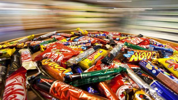 Eine große Auswahl an verschiedenen Schokoriegeln, darunter KitKat und Smarties, liegt auf einem Tisch.