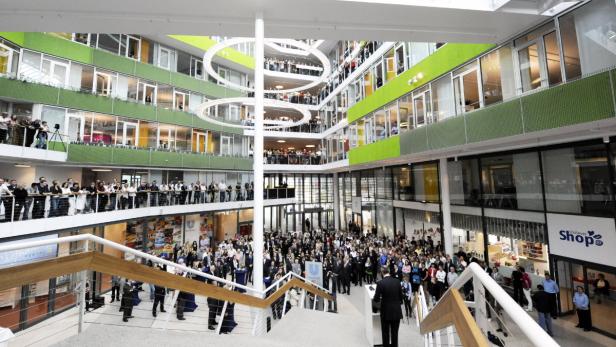 Eine große Menschenmenge versammelt sich im Atrium eines mehrstöckigen Bürogebäudes.