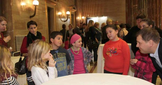 Eine Gruppe von Kindern und Erwachsenen steht in einem Raum mit warmem Licht.