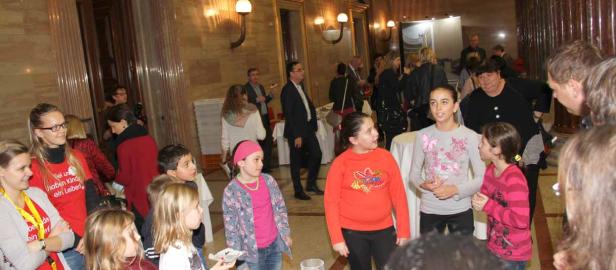 Eine Gruppe von Kindern und Erwachsenen steht in einem eleganten Raum zusammen.