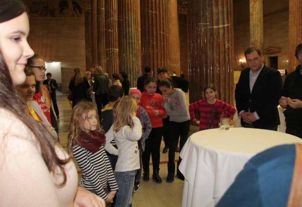 Eine Gruppe von Kindern steht in einem Raum mit hohen Säulen.