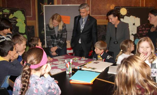 Eine Gruppe von Kindern sitzt mit Erwachsenen an einem Tisch und arbeitet an einem Projekt.
