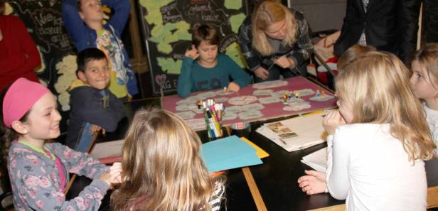 Eine Gruppe Kinder sitzt an einem Tisch und spielt ein Spiel.