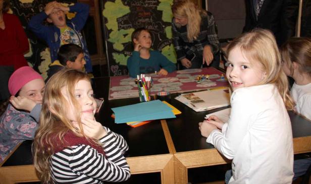 Eine Gruppe Kinder sitzt an einem Tisch und spielt ein Spiel.