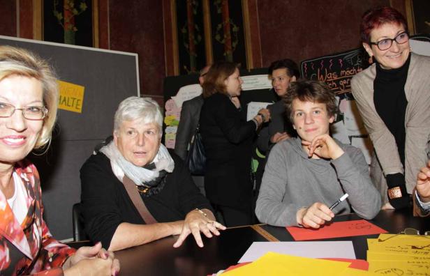 Eine Gruppe von Menschen steht an einem Tisch mit farbigem Papier und Stiften.