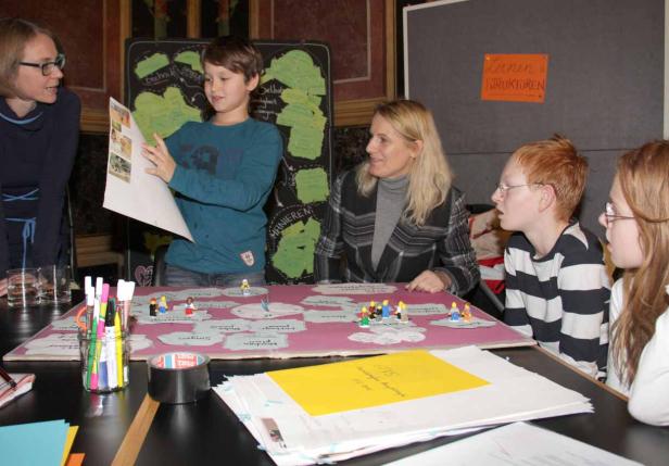 Eine Gruppe von Personen arbeitet an einem Projekt mit Legofiguren und Karten.