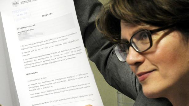 Eine Frau mit Brille liest ein Dokument mit dem Titel „Beschluss“.