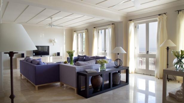 Ein helles Wohnzimmer mit lila Sofas und Blick auf das Meer.