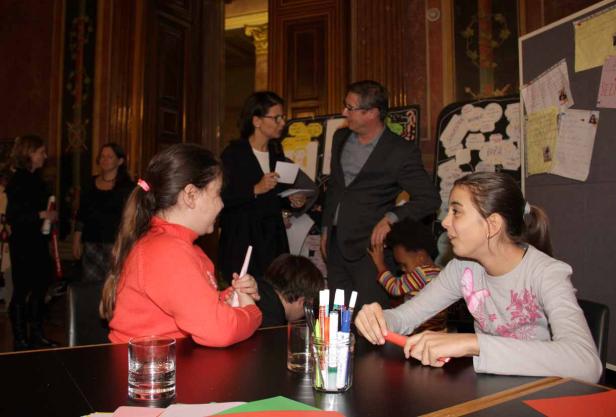 Zwei Mädchen sitzen an einem Tisch und basteln mit Stiften und Papier.