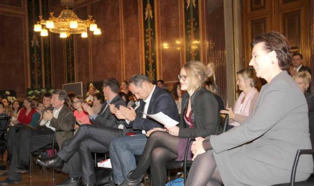 Zuschauer applaudieren bei einer Veranstaltung in einem eleganten Saal.