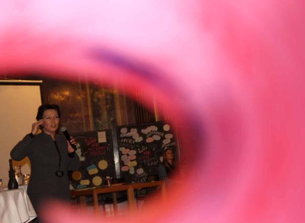 Eine Frau hält ein Mikrofon und spricht vor Publikum.