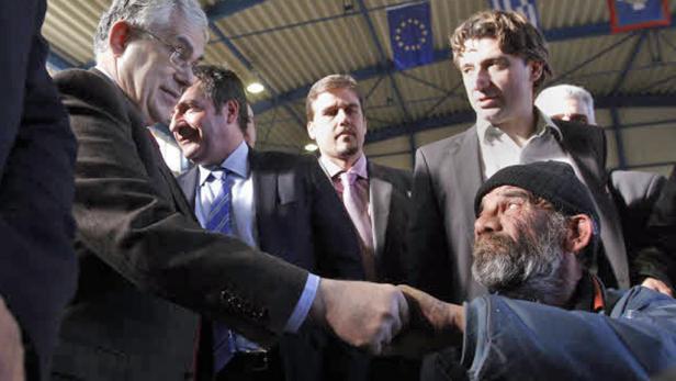 Ein Mann im Anzug schüttelt die Hand eines Mannes mit Bart und Mütze.