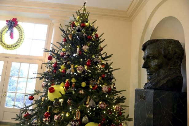 Ein geschmückter Weihnachtsbaum steht neben einer Büste von Abraham Lincoln.