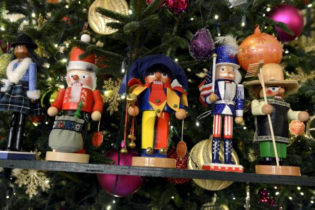 Eine Reihe von Nussknackern steht vor einem Weihnachtsbaum.