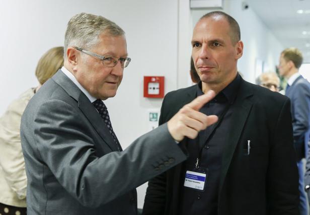 Zwei Männer in Anzügen unterhalten sich in einem Flur.