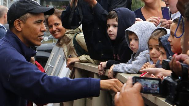 Barack Obama begrüßt Kinder hinter einer Absperrung.