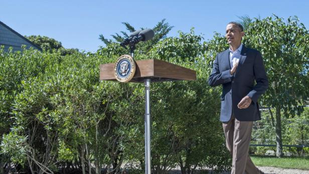 Barack Obama steht an einem Rednerpult im Freien.