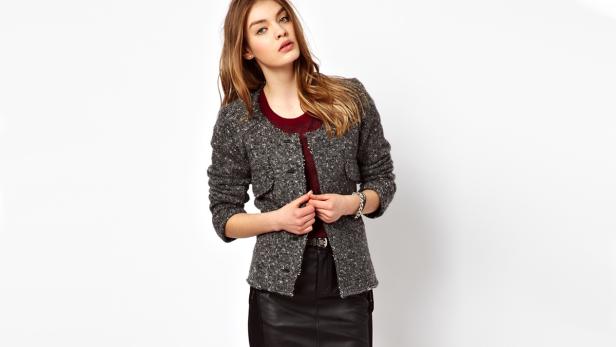 Eine Frau trägt eine graue Tweedjacke und einen schwarzen Lederrock.