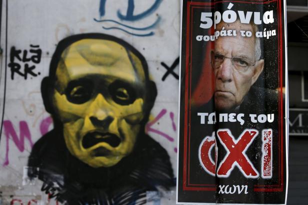 Ein gelbes Graffiti-Porträt und ein politisches Plakat an einer Wand.