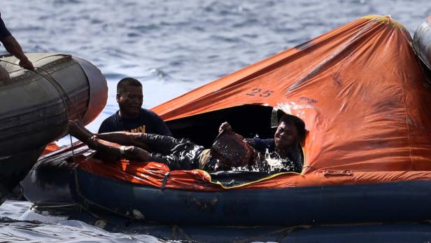 Zwei Männer in einem orangefarbenen Rettungsboot auf dem offenen Meer.