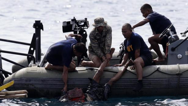 Männer ziehen eine Person aus dem Wasser in ein Schlauchboot.