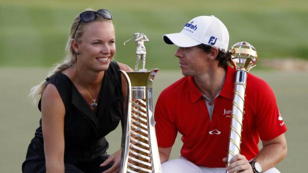 Caroline Wozniacki und Rory McIlroy mit Golftrophäen.