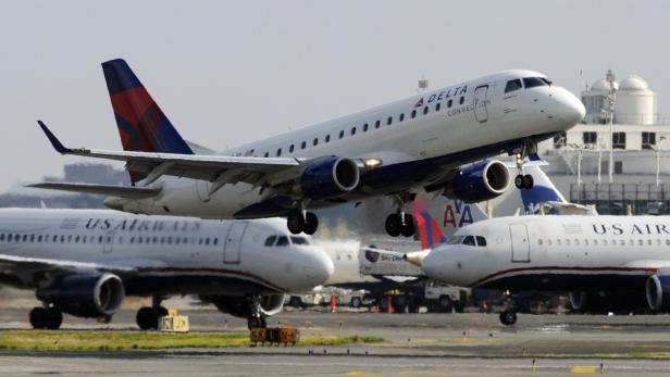 Ein Delta Connection Flugzeug hebt ab, während andere Flugzeuge am Boden stehen.